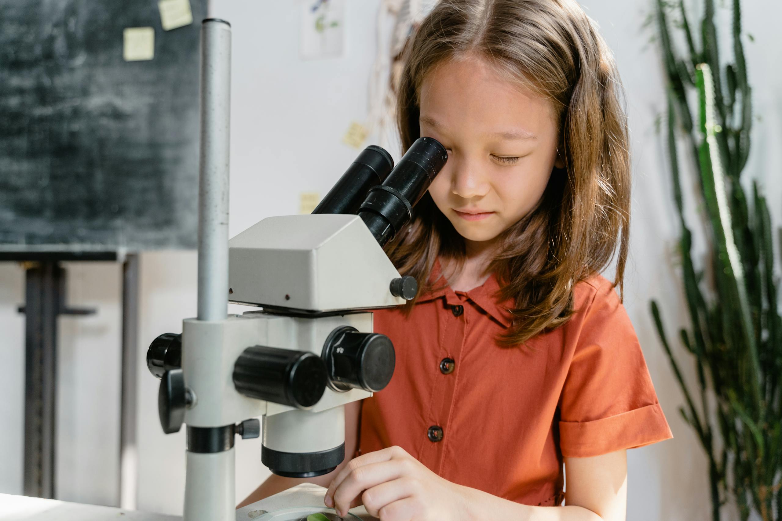 Close-Up Photo of a Smart Girl Looking at the Microscope